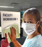 women wearing a mask cleaning a tactile sign with a cloth rag