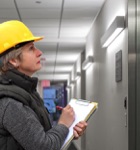 woman in a hard hat and clipboard inspecting the interior of a building